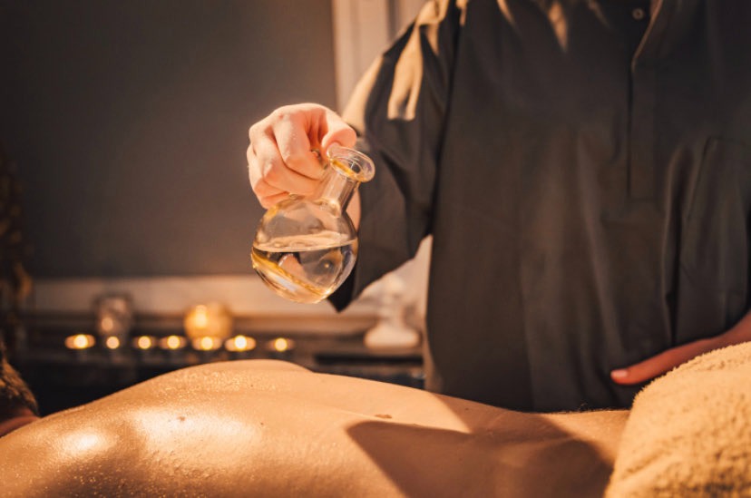 Moment rozlania ciepłej oliwki na ciało klienta.