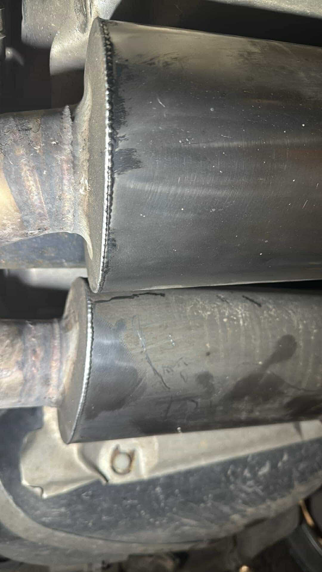 Dwa metalowe, cylindryczne elementy połączone spoiną, widoczne ślady obróbki i niedoskonałości powierzchni.