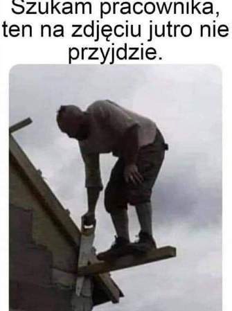 Mężczyzna w krótkich spodenkach i koszulce, stojący na wąskiej desce przymocowanej do dachu, przecina deskę piłą ręczną na tle pochmurnego nieba.