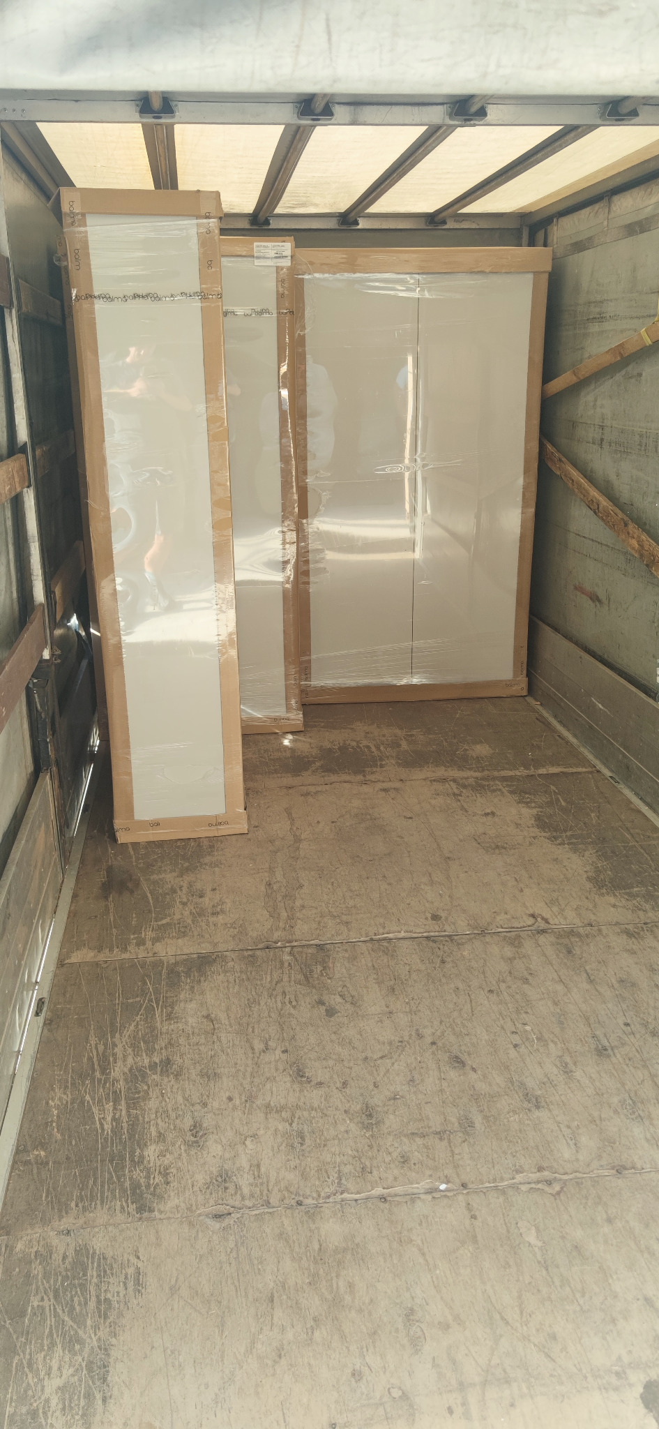 Meble zapakowane w folię i karton, przewożone w przestrzeni ładunkowej samochodu dostawczego.