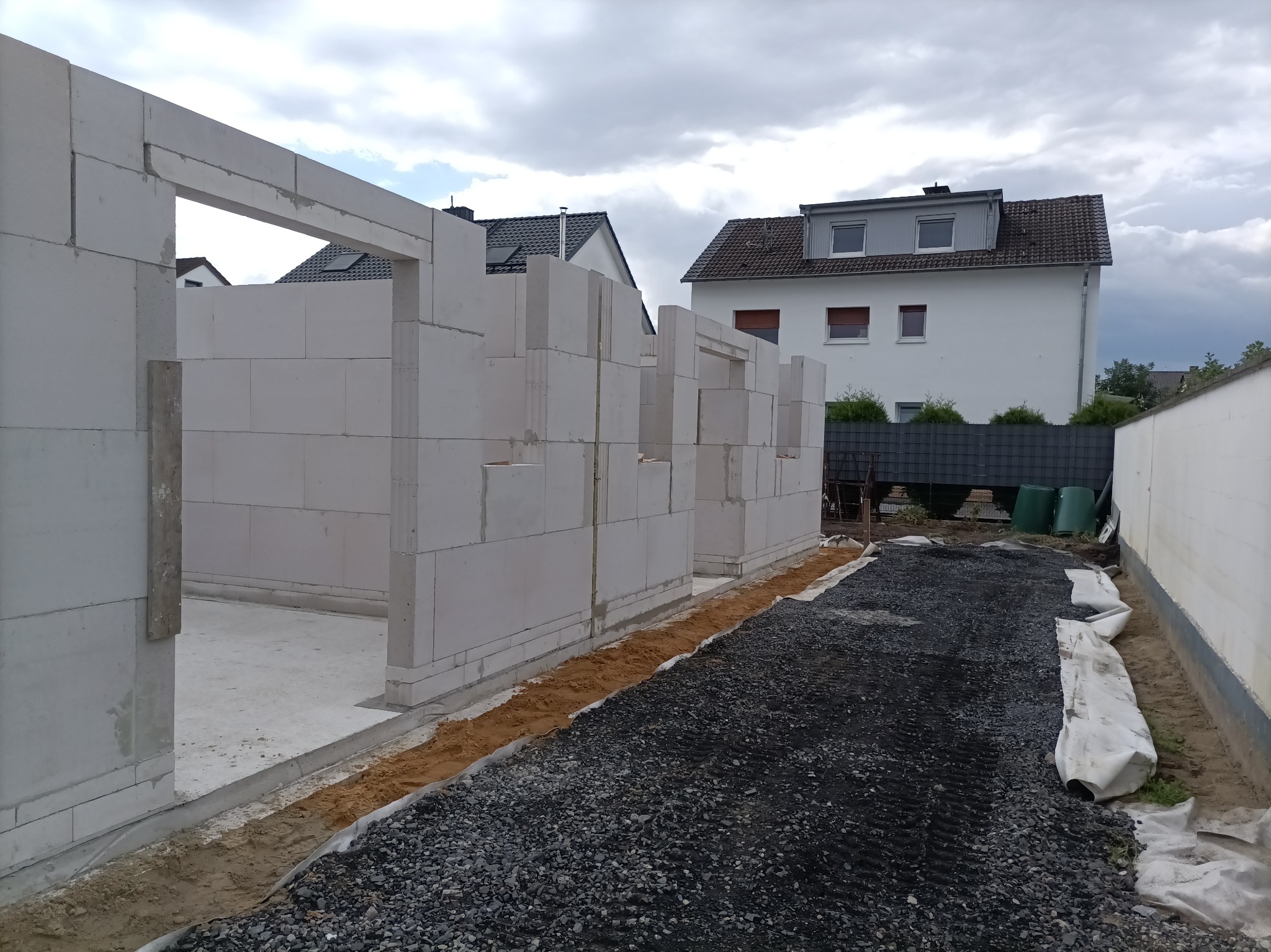 Wznoszenie ścian z bloczków betonu komórkowego Ytong w Lublinie. Widoczne fundamenty i częściowo wymurowane ściany budynku w stanie surowym otwartym.