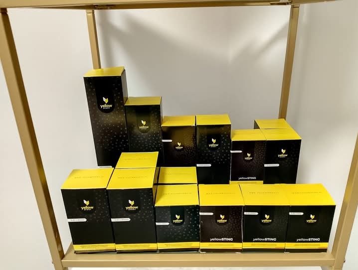 Różne rozmiary czarno-żółtych pudełek z logo na złotej półce.