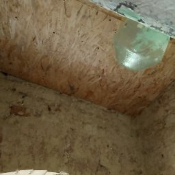 Usługi remontowo-budowlane - Surowe wnętrze poddasza z widoczną płytą OSB na skosie dachu i fragmentami ocieplenia z folią w narożniku.