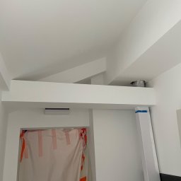 Stanislav Papkov - Wnętrze w trakcie prac wykończeniowych: zabezpieczone folią drzwi, pomalowany sufit z widocznymi belkami, zamontowany klimatyzator i fragment wentylacji.