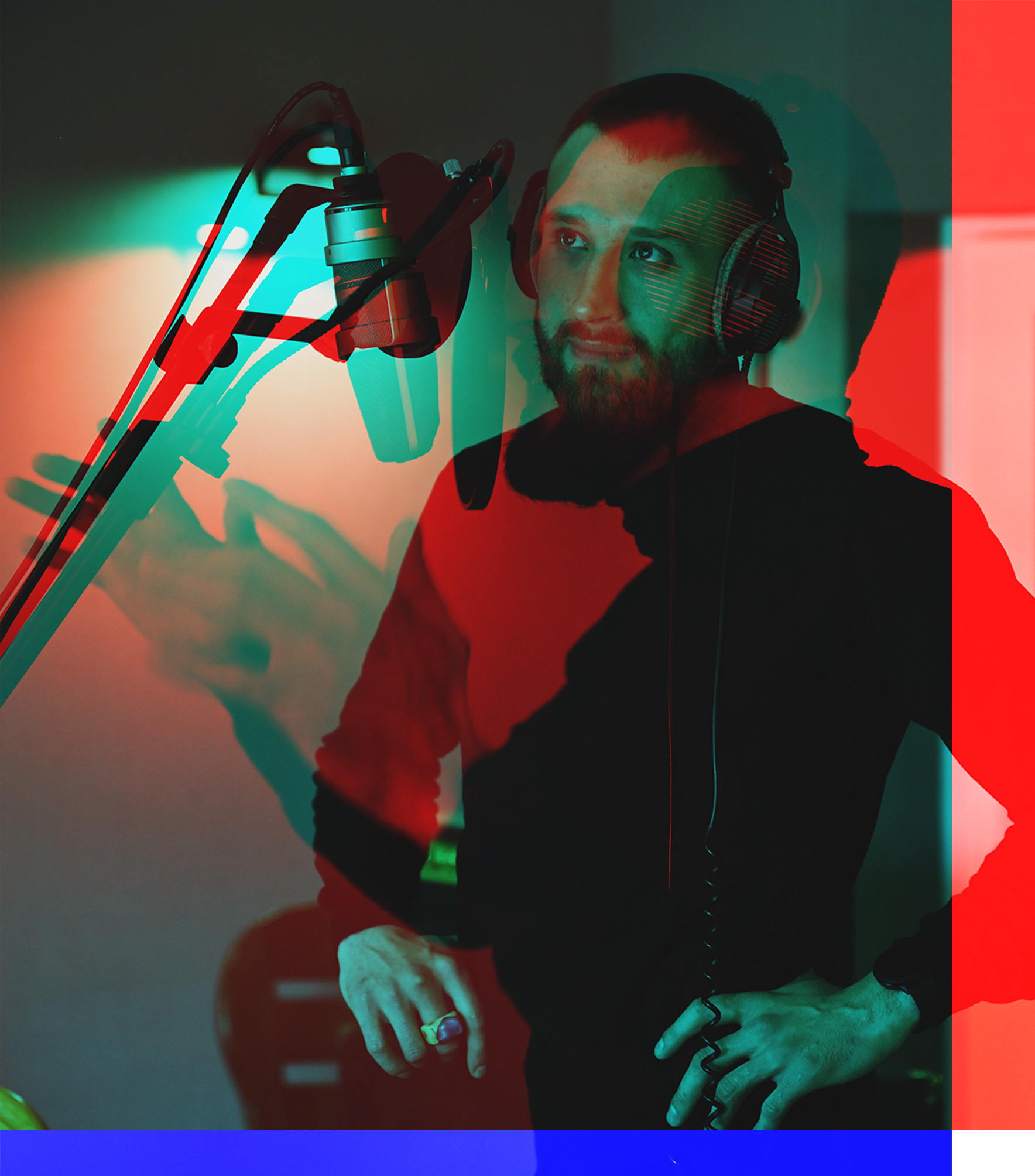 Mężczyzna z brodą w słuchawkach studyjnych, stojący przed mikrofonem w studio nagraniowym, z efektem wizualnym anaglifu (czerwono-cyjanowym)