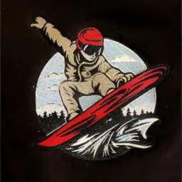 Czarna tkanina z naszywką przedstawiającą snowboardzistę w kasku i goglach, na tle gór i fal, wykonaną techniką haftu.