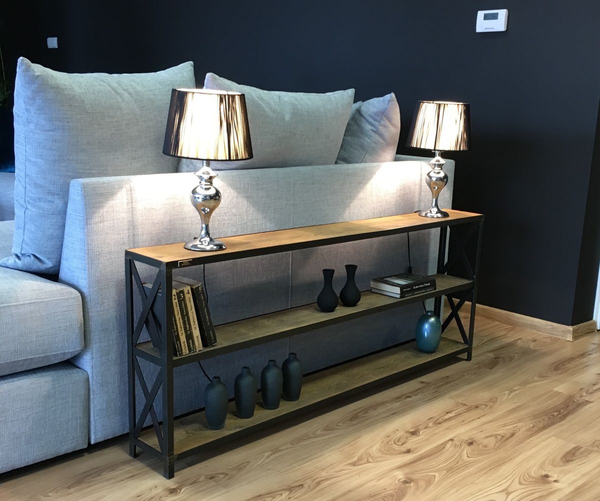 Metalowa konsola z drewnianymi półkami w stylu industrialnym, ustawiona za szarą sofą, z czarnymi wazonami i książkami na półkach, oświetlona dwiema lampkami nocnymi z czarnymi abażurami.