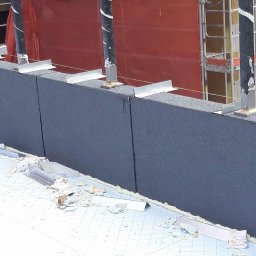 Usługi dekarskie Monro Monika Nowak - Montaż izolacji termicznej na dachu z widocznymi elementami mocującymi i fragmentami materiałów izolacyjnych, na tle konstrukcji rusztowania.