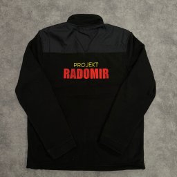 PIXEL HAFT - Czarna bluza polarowa z krótkim zamkiem, z nadrukiem 'Projekt Radomir' w kolorze czerwonym, leżąca na szarym tle.