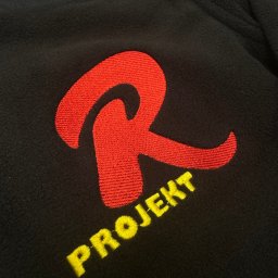 PIXEL HAFT - Czarna bluza polarowa z wyhaftowanym czerwonym logo litery 'R' i żółtym napisem 'PROJEKT' poniżej.