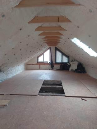 Poddasze po ociepleniu pianką PUR z widoczną drewnianą konstrukcją dachu i oknami dachowymi, częściowo wyłożone płytami OSB z otworem rewizyjnym.