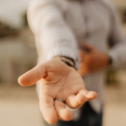 Mikołaj Londo Coco Bystre Rozwiązania - Otwarta dłoń z pierścionkiem, wyciągnięta w geście zaproszenia lub pomocy, na rozmytym tle osoby w koszuli, z delikatnym, naturalnym oświetleniem.