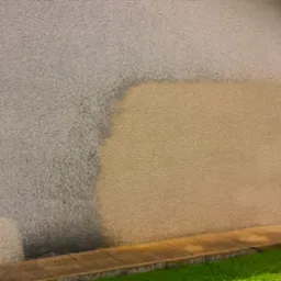 Fragment elewacji budynku z widoczną r&oacute;żnicą w kolorze i czystości, prawdopodobnie po częściowym czyszczeniu. G&oacute;rna lewa część jest szara i zabrudzona, a dolna prawa część jest jaśniejsza...