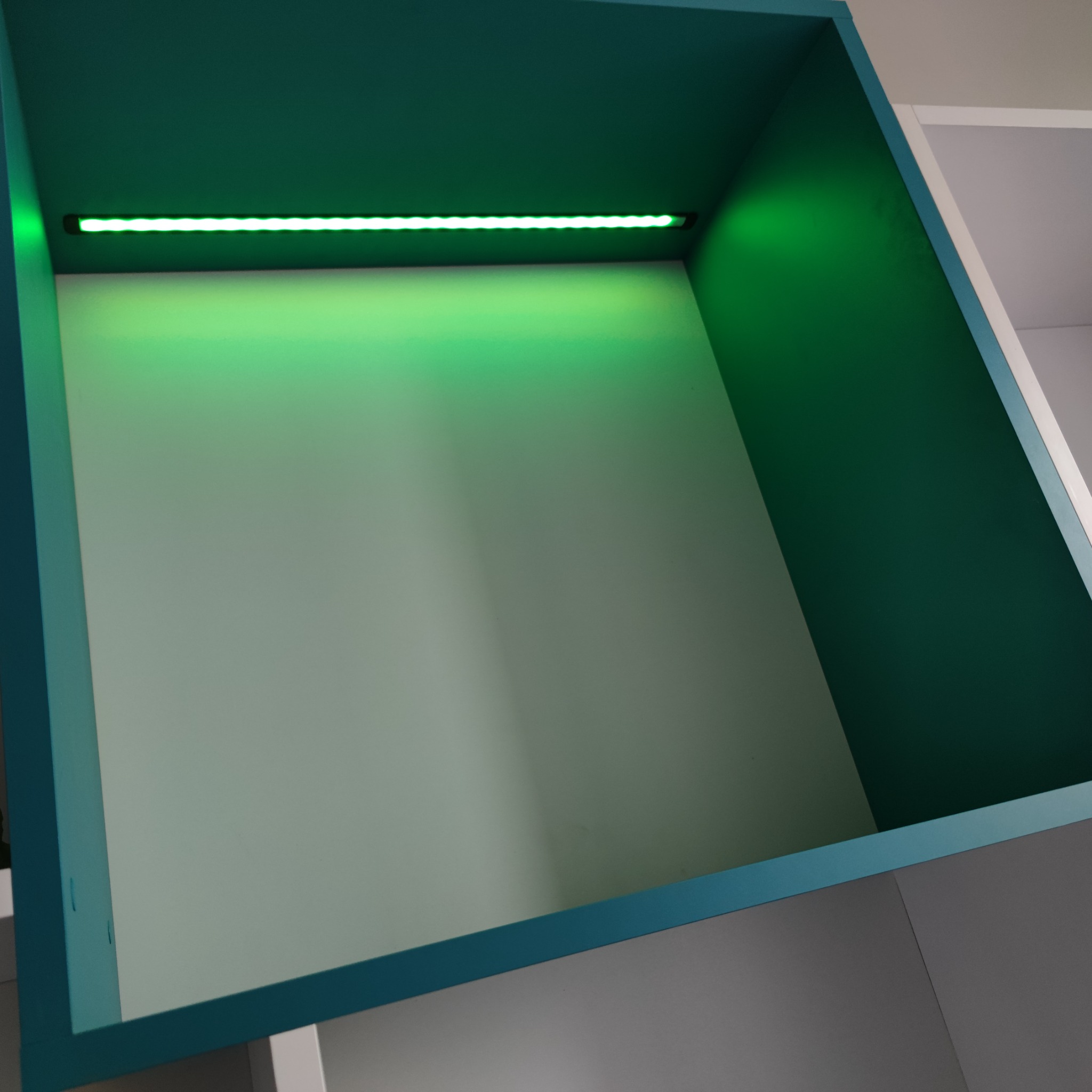 Półka wnękowa z oświetleniem LED, turkusowa rama, szare wnętrze, nowoczesny design.