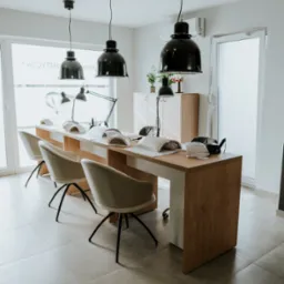 Salon kosmetyczny: Stanowiska do manicure z lampami UV, kremowymi krzesłami i wiszącymi czarnymi lampami, widok na jasne wnętrze z oknami.