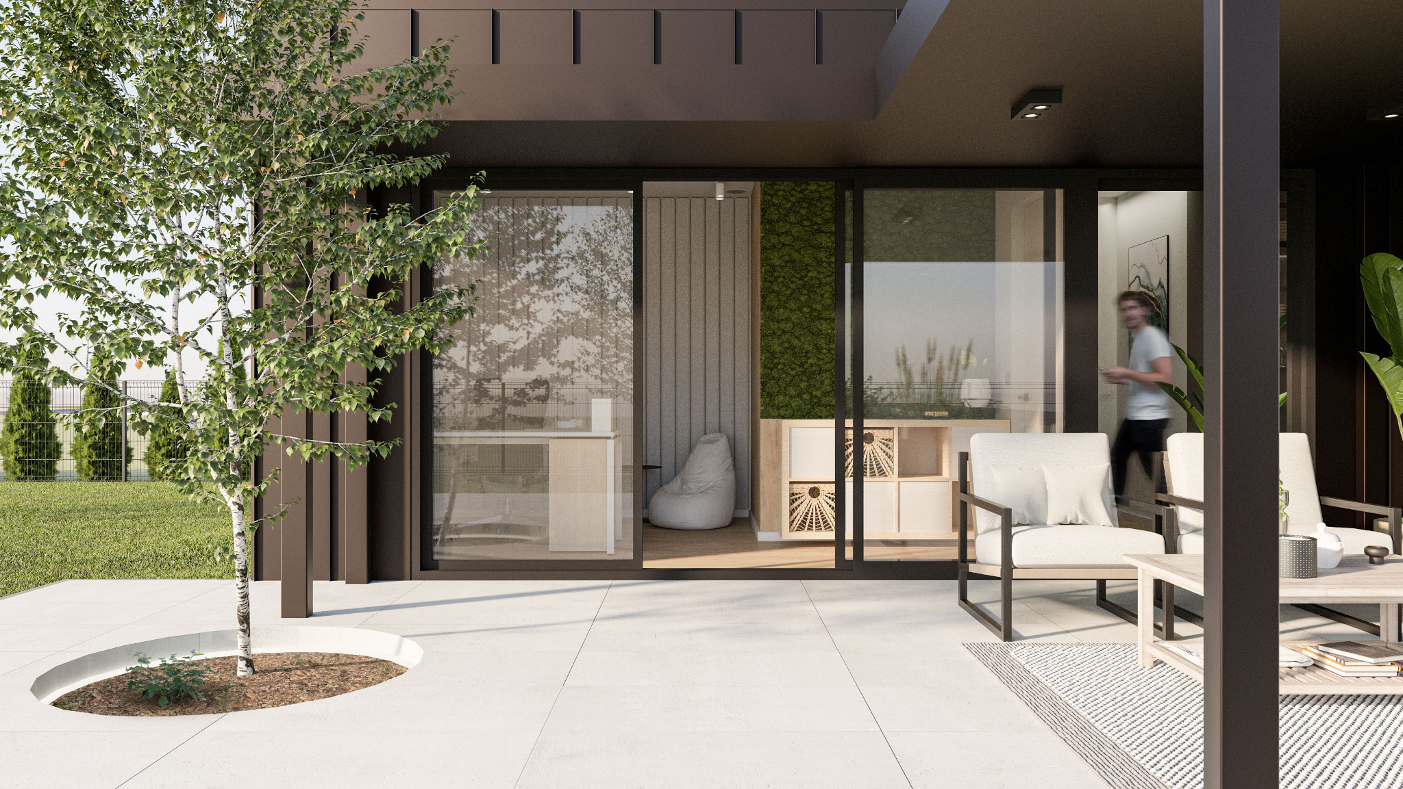 Nowoczesny taras z białymi płytami, drzewem w okrągłej donicy, meblami wypoczynkowymi i widokiem na wnętrze domu przez przesuwne szklane drzwi.