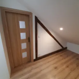 Gotowe poddasze z drewnianą podłogą, drewnianą ramą konstrukcyjną i nową, drewnianą, przeszkloną wewnętrzną stolarką drzwiową.