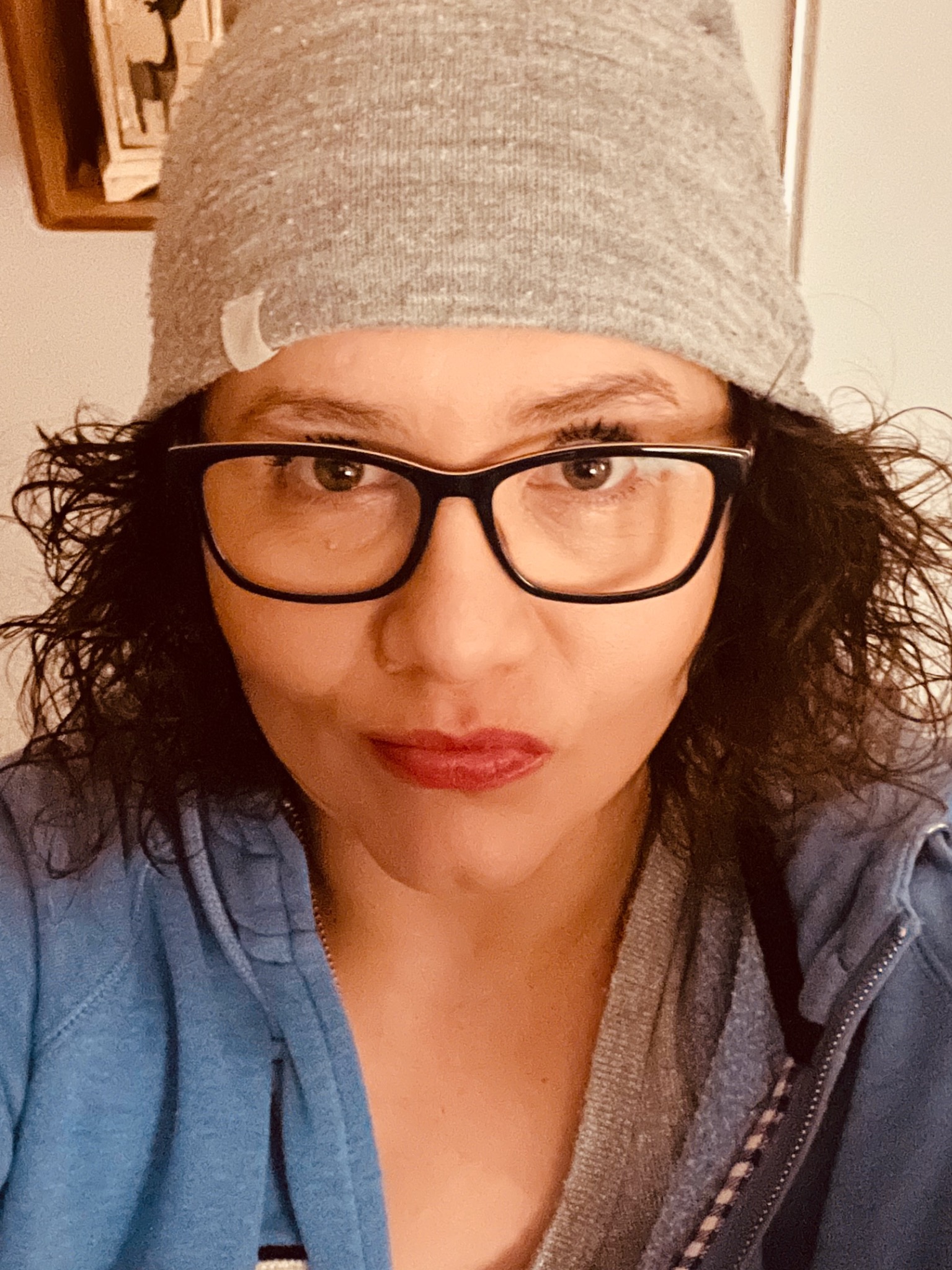 Portret kobiety w okularach z czarnymi oprawkami, szarej czapce i niebieskiej bluzie z zamkiem błyskawicznym, patrzącej wprost w obiektyw.
