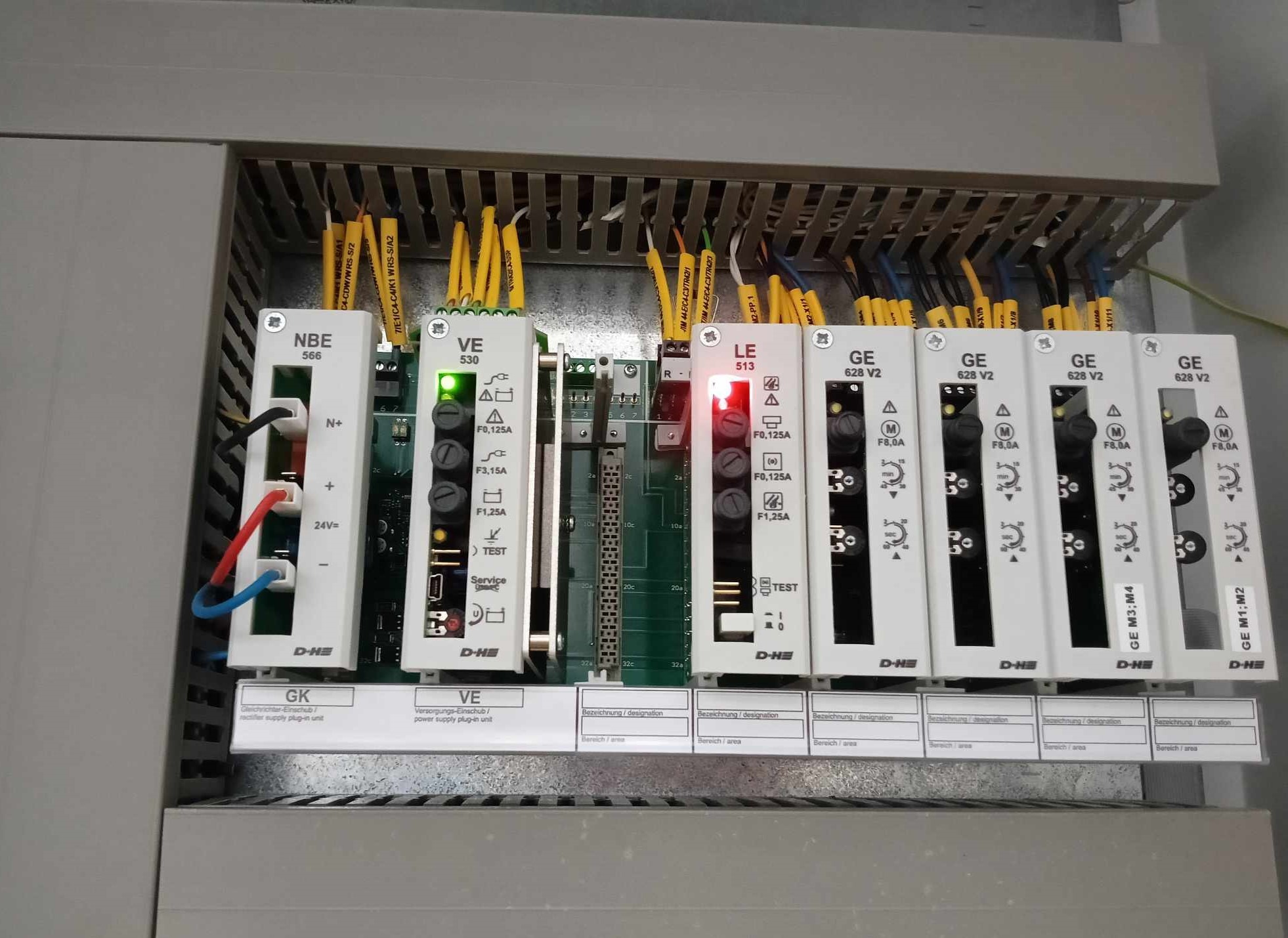 Panel sterowniczy z modułami zasilania, widoczne przewody, diody LED i oznaczenia na modułach.