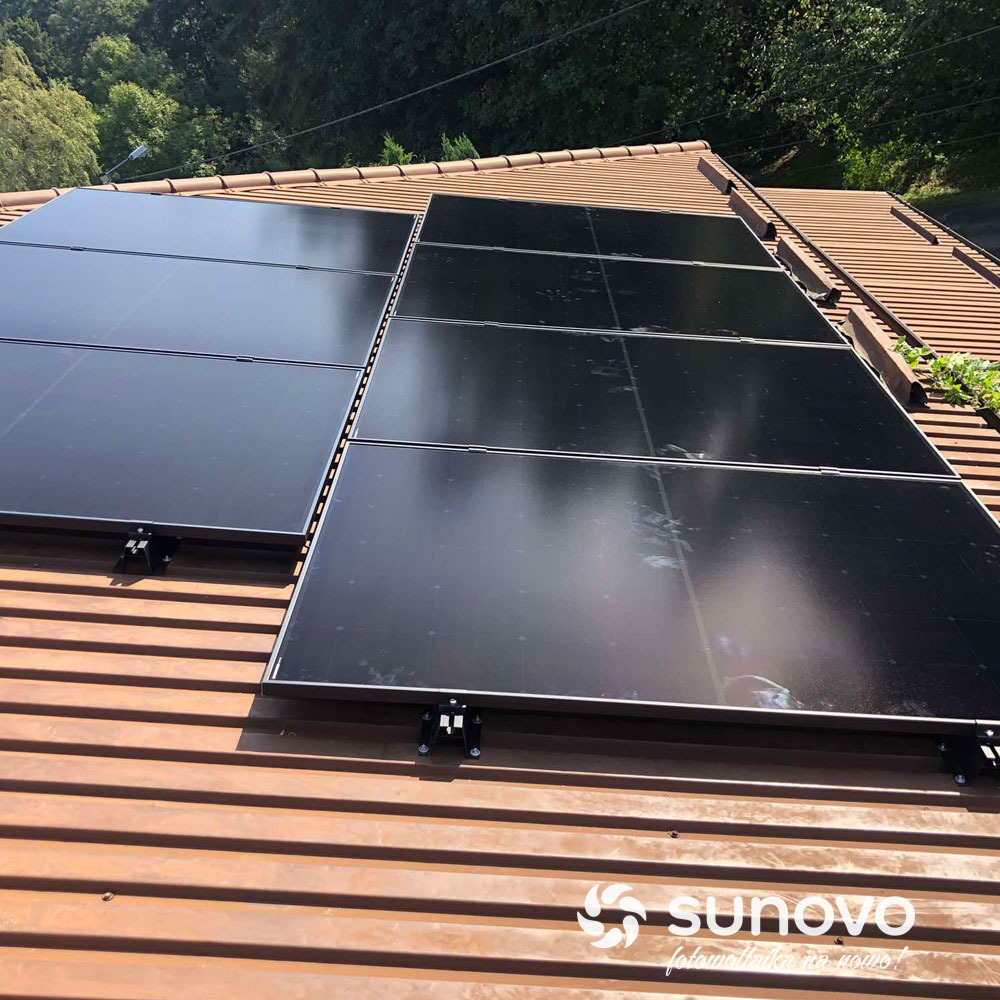 Ciemne panele słoneczne zamontowane na brązowym dachu z widocznym logotypem Sunovo w prawym dolnym rogu.
