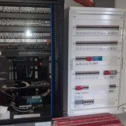 Rozdzielnica elektryczna z bezpiecznikami i szafa rack z patch panelem, switchami i okablowaniem, widoczne oznaczenia obwodów i portów.