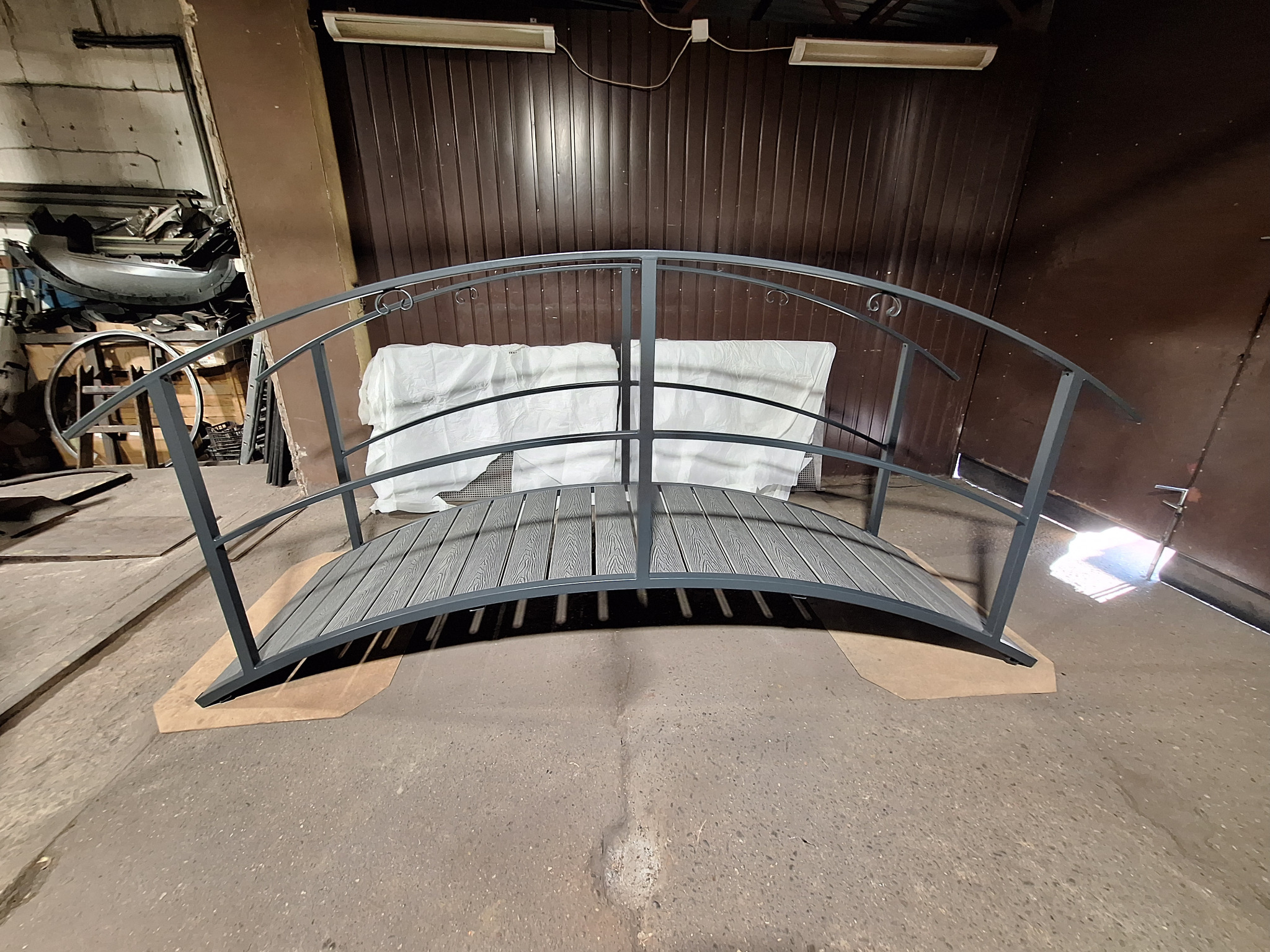 Dekoracyjny mostek z metalową konstrukcją i drewnianym pomostem, wykonany w Mysłowicach. Element małej architektury ogrodowej, prezentowany w warsztacie.