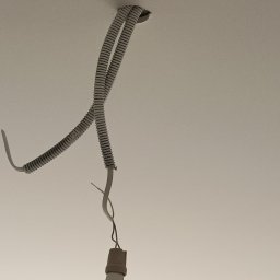 ARKADIUSZ ŻOCZEK - Biały sufit z wystającymi przewodami elektrycznymi w peszlu, przygotowanymi do podłączenia oświetlenia. Widoczne otwory montażowe.