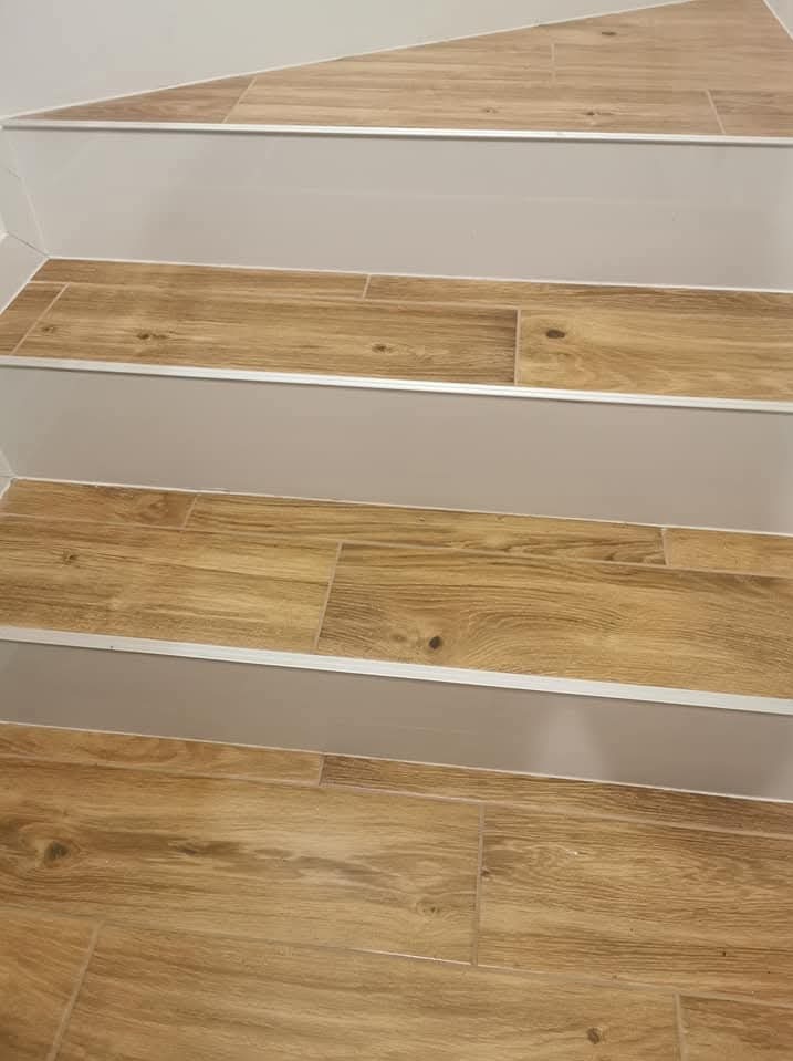 Schody wyłożone płytkami imitującymi drewno, z aluminiowymi listwami krawędziowymi, widok z dołu.