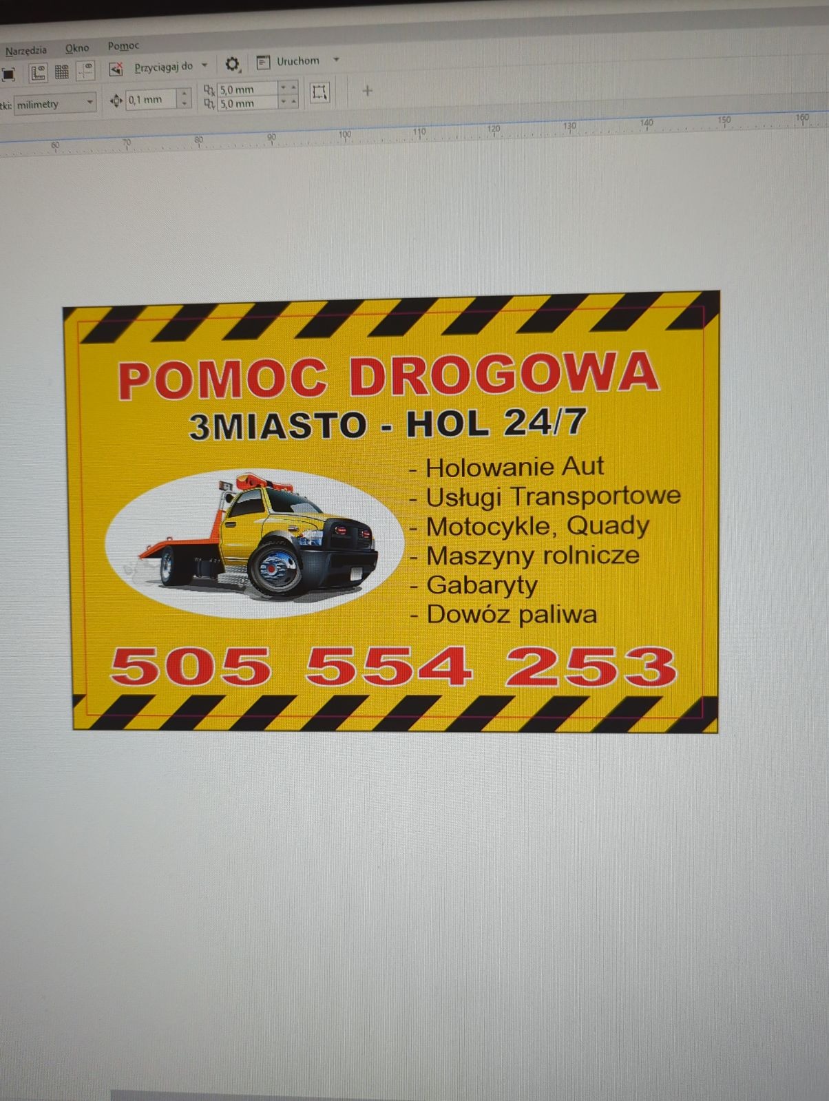 Grafika reklamowa pomocy drogowej z Żuławki, prezentująca żółtą lawetę i numer telefonu alarmowego na żółtym tle z czarnymi pasami ostrzegawczymi.