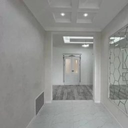 Serhii Melnyk - Nowoczesny korytarz z białymi ścianami o fakturze, marmurową podłogą, lustrem o geometrycznym wzorze i kwadratowymi lampami w suficie podwieszanym