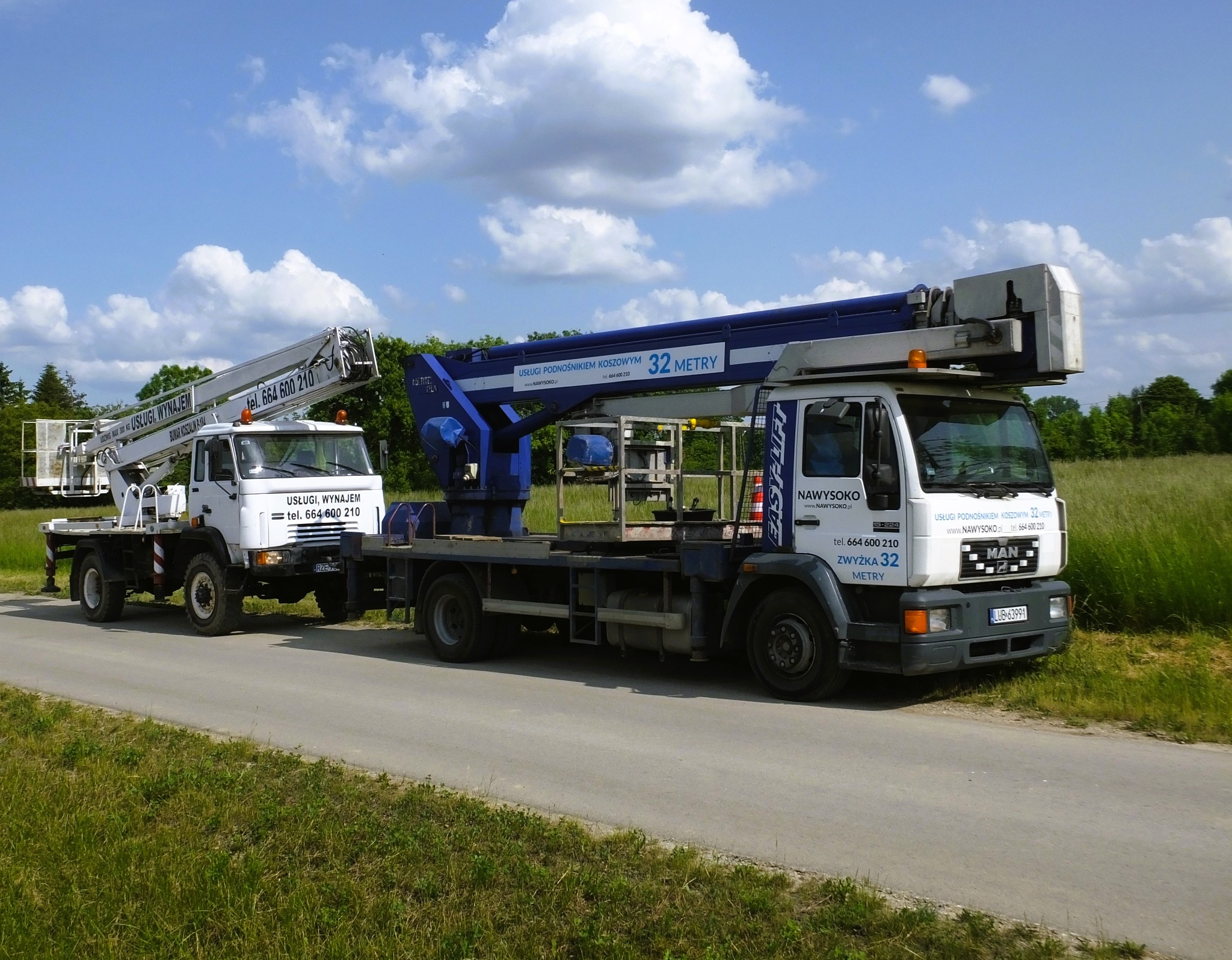 Dwa samochody ciężarowe z podnośnikami koszowymi zaparkowane obok siebie na asfaltowej drodze, widoczne logo firmy 'NAWYSOKO' oraz informacja '32 metry' na wysięgniku.