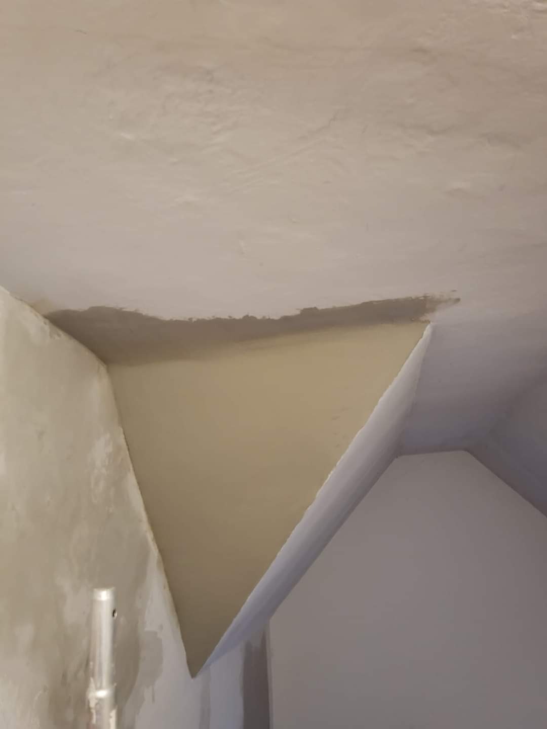 Fragment sufitu i ściany po szpachlowaniu, widoczne nierówności powierzchni i ślady po narzędziach, przygotowane do dalszych prac wykończeniowych.