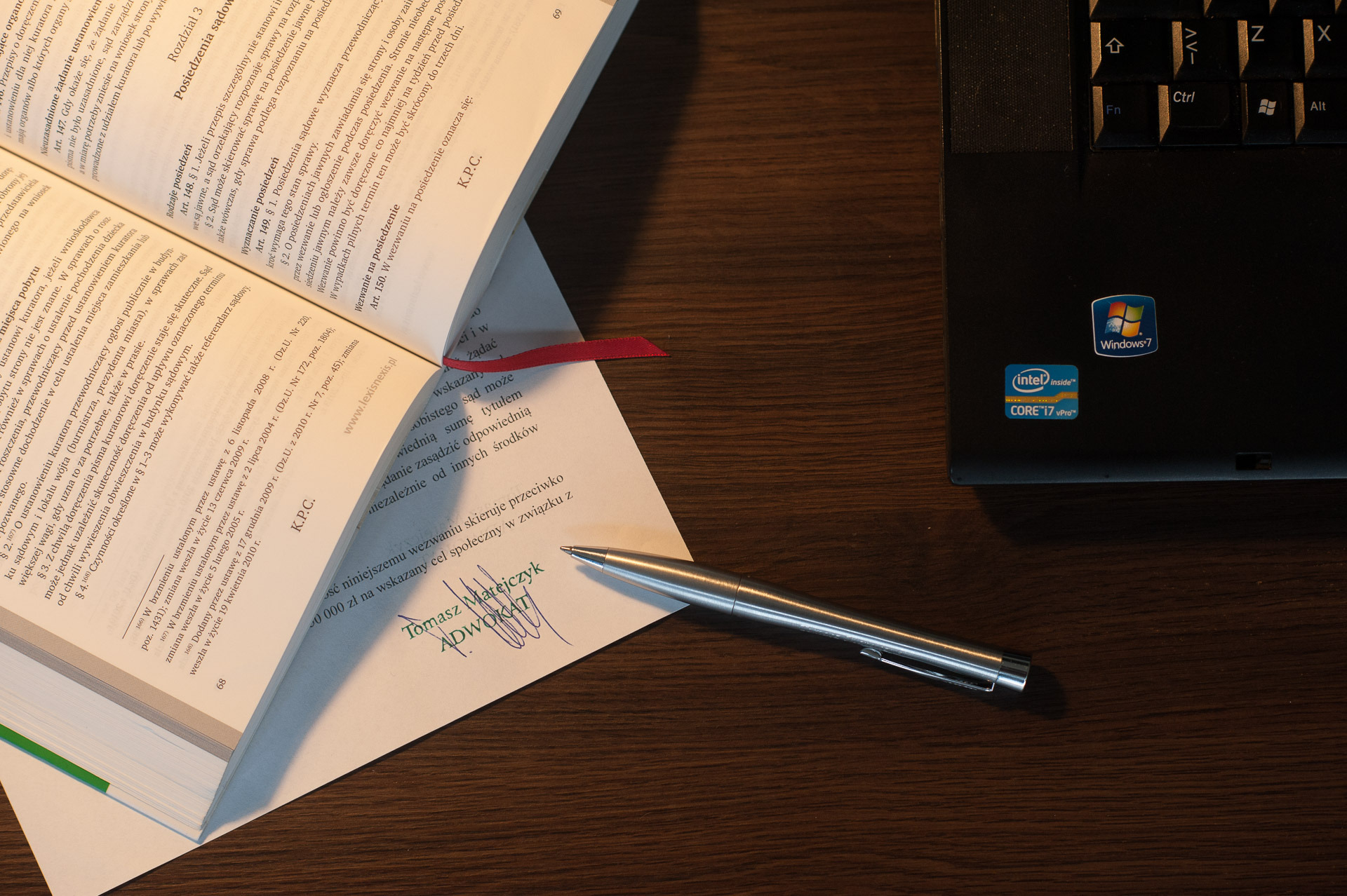 Dokument z podpisem adwokata Tomasza Matejczyka z Chrzanowa, leżący obok otwartego kodeksu postępowania cywilnego i laptopa.