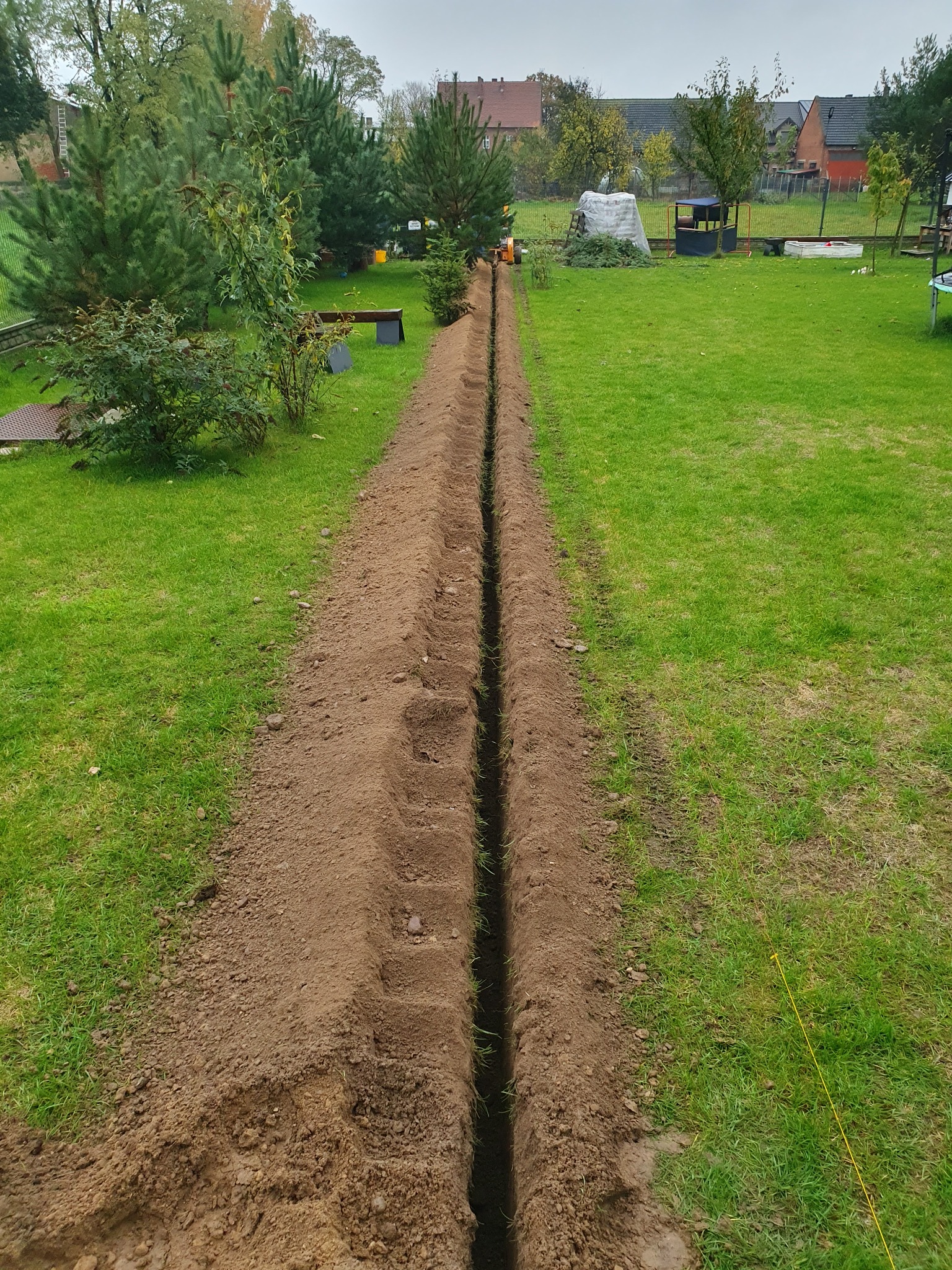 Długi, wąski wykop w ziemi na trawniku w Słupii pod Kępnem, przygotowany pod instalację, widok z góry.