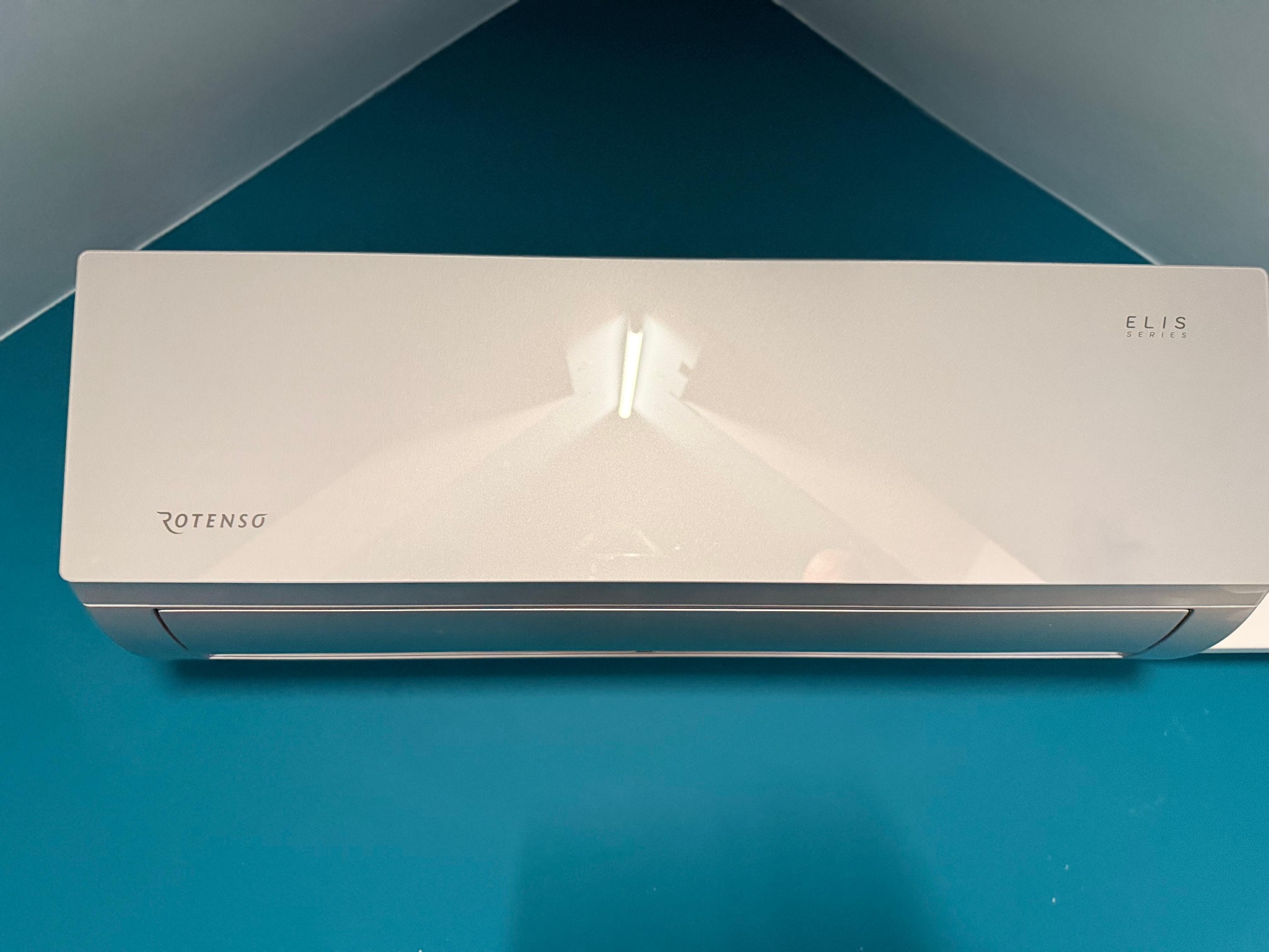 Biała jednostka klimatyzacji Rotenso Elis Series zamontowana na turkusowej ścianie w domu w Czapurach.