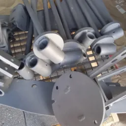 Metalowe elementy konstrukcyjne, po obróbce, ułożone na palecie, widoczne otwory montażowe i ślady po procesie czyszczenia.