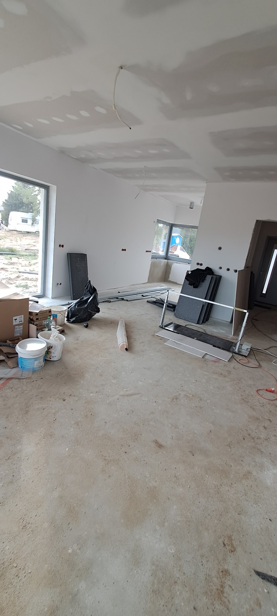 Wnętrze w Sychowie w trakcie szpachlowania sufitu, widoczne puszki z farbą, narzędzia i elementy konstrukcyjne.