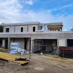 BP Construction BARTŁOMIEJ POLAK - Budowa domu jednorodzinnego w stanie surowym otwartym, widoczne bloczki H+H, szalunki, rusztowania i materiały budowlane. Ujęcie w słoneczny dzień.