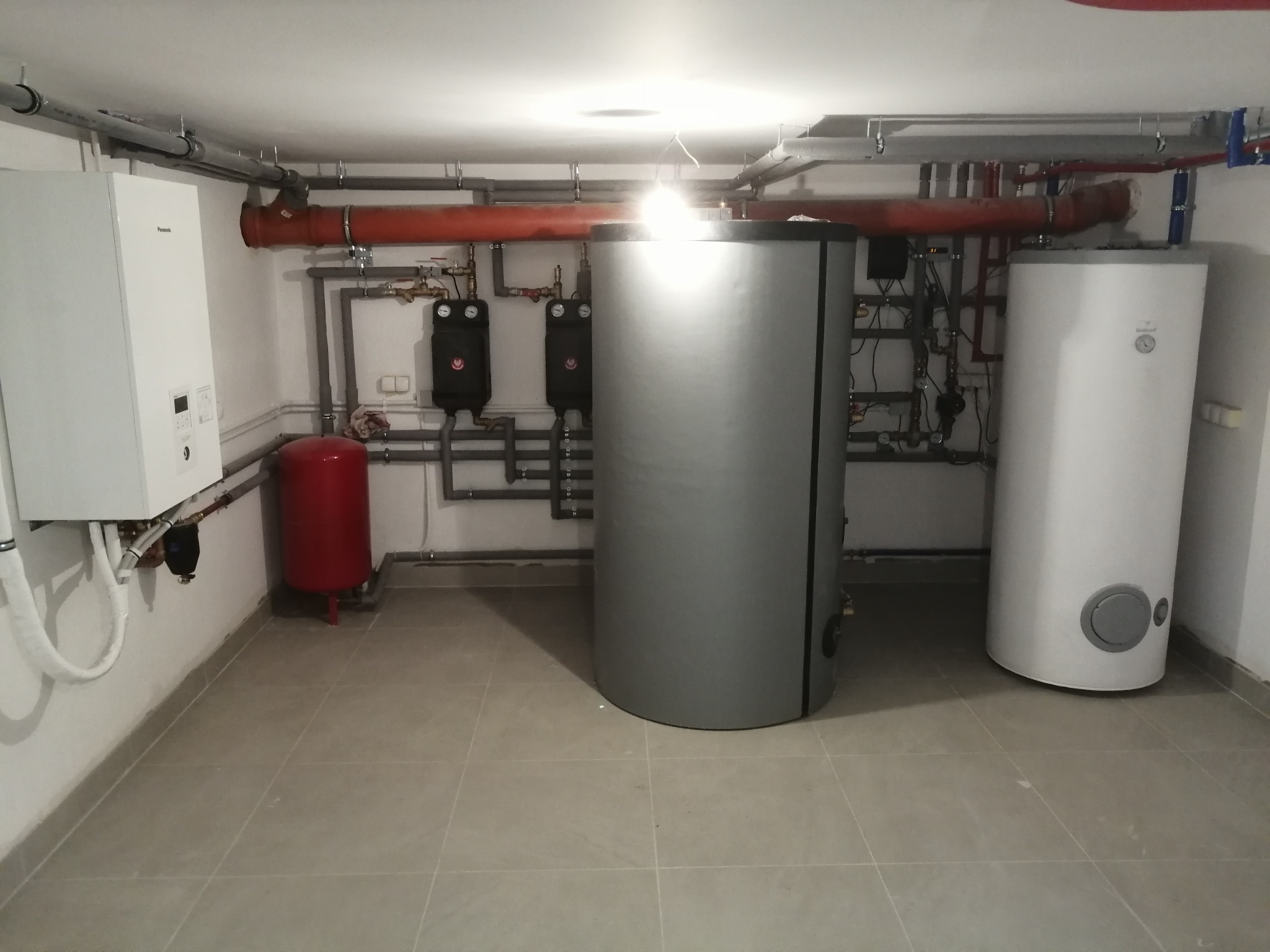 Kotłownia z zainstalowanym piecem gazowym, zasobnikiem ciepłej wody, zbiornikiem wyrównawczym i rozbudowaną instalacją hydrauliczną z rurami miedzianymi i stalowymi.