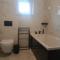 Nowoczesna łazienka z wanną obudowaną czarnymi, błyszczącymi płytkami, wiszącą toaletą i czarnymi akcesoriami na tle marmurowych płytek.