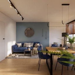 Sopata Studio Design Katarzyna Sopata - Nowoczesny salon z jadalnią, gdzie niebieska sofa stoi przy turkusowej ścianie z okrągłym lustrem. Drewniany stół z niebieskimi welurowymi krzesłami, oświetlenie szynowe i duża paproć na pierwszym...