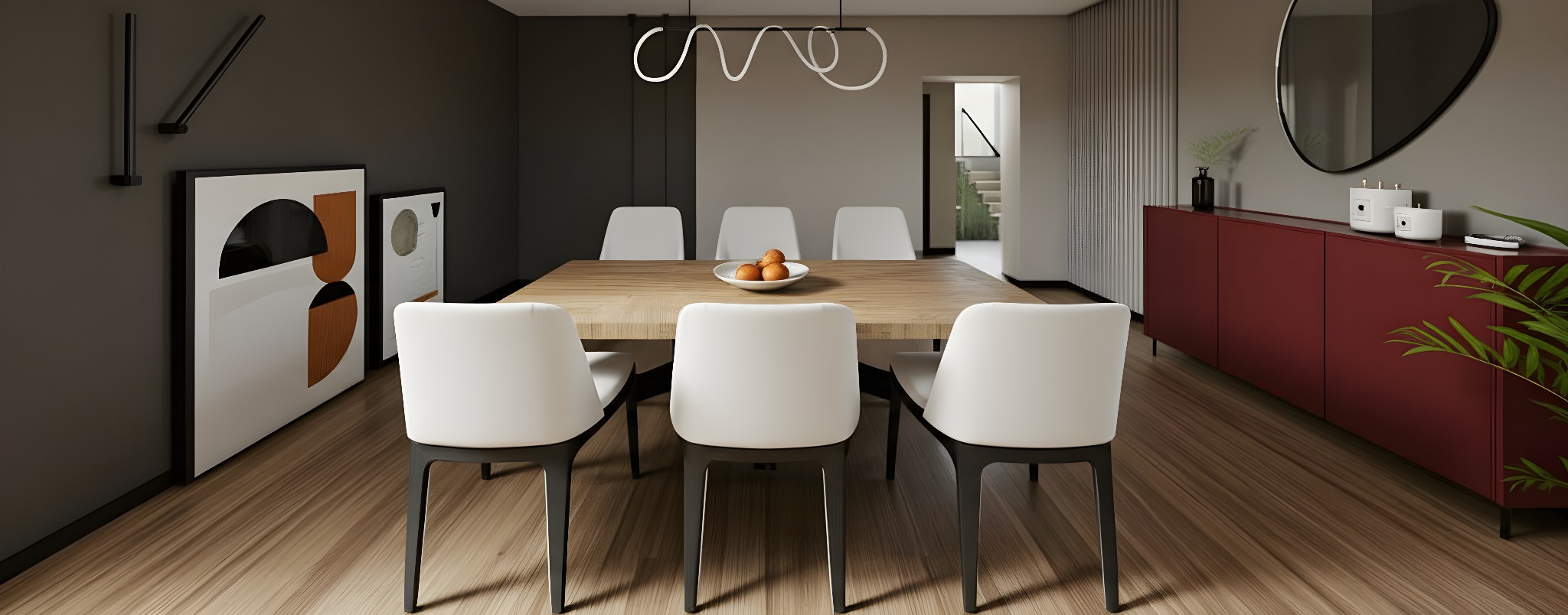 Nowoczesna jadalnia z drewnianym stołem, białymi krzesłami i burgundową komodą. Na stole misa z owocami, a nad nim designerska lampa. Minimalistyczne obrazy na ścianie.