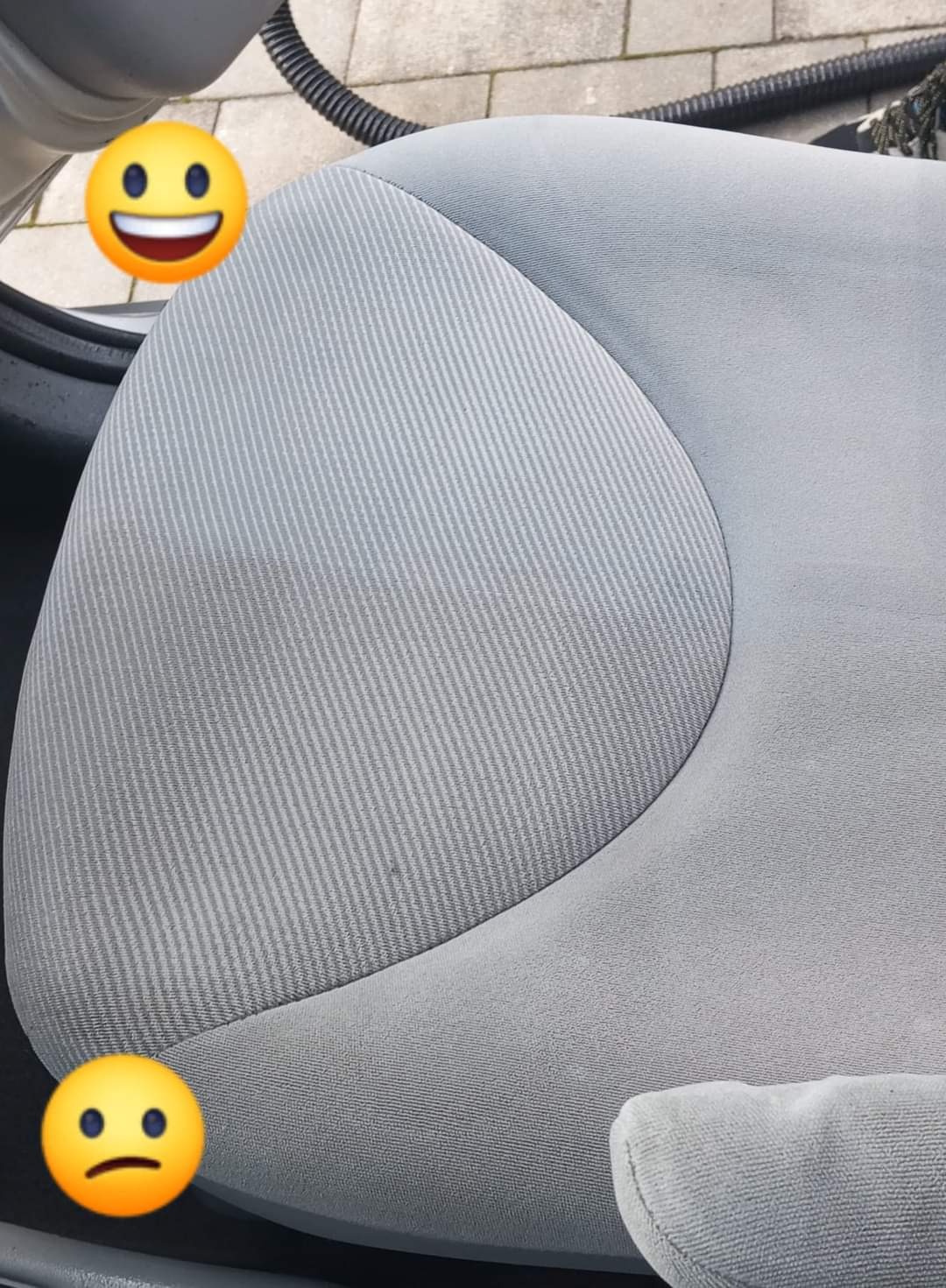 Częściowo wyczyszczone, jasnoszare siedzenie samochodowe z widoczną różnicą w kolorze i strukturze materiału, zarys odkurzacza w tle.