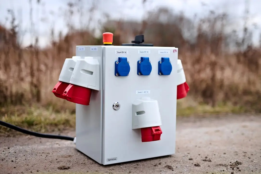 Rozdzielnica elektryczna przenośna z gniazdami różnego typu (230V i 400V) oraz wyłącznikiem bezpieczeństwa, umieszczona na zewnątrz na ziemi.