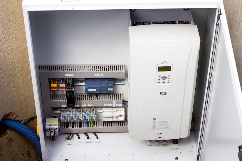 Wnętrze szafy sterowniczej z modułem falownika LS i elementami automatyki Siemens, widoczne okablowanie i wentylatory chłodzące.