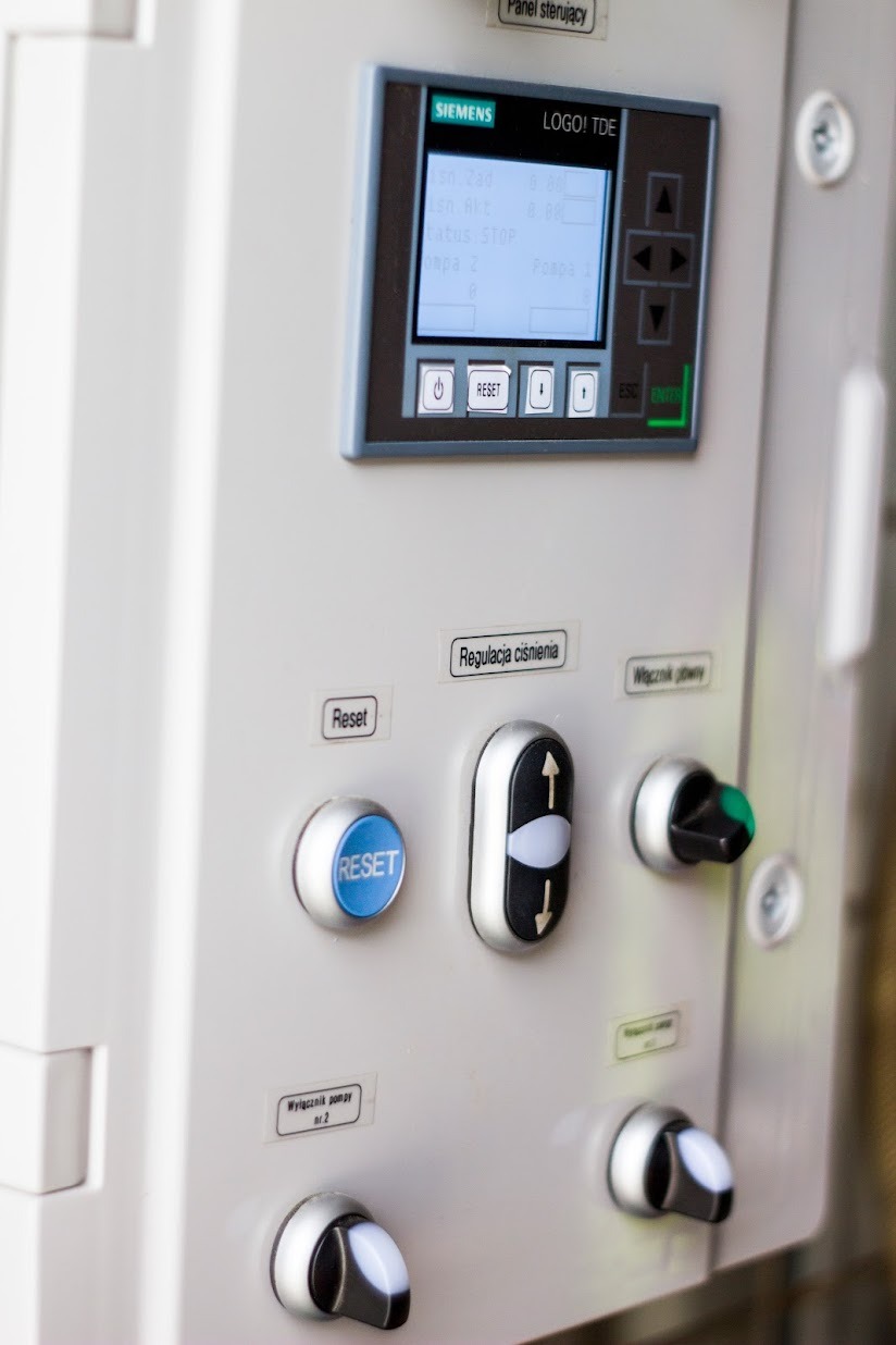 Panel sterowania Siemens LOGO! TDE z wyświetlaczem, przyciskami (Reset, włącznik), przełącznikami i etykietami (Regulacja ciśnienia, Wyłącznik pompy nr. 2).