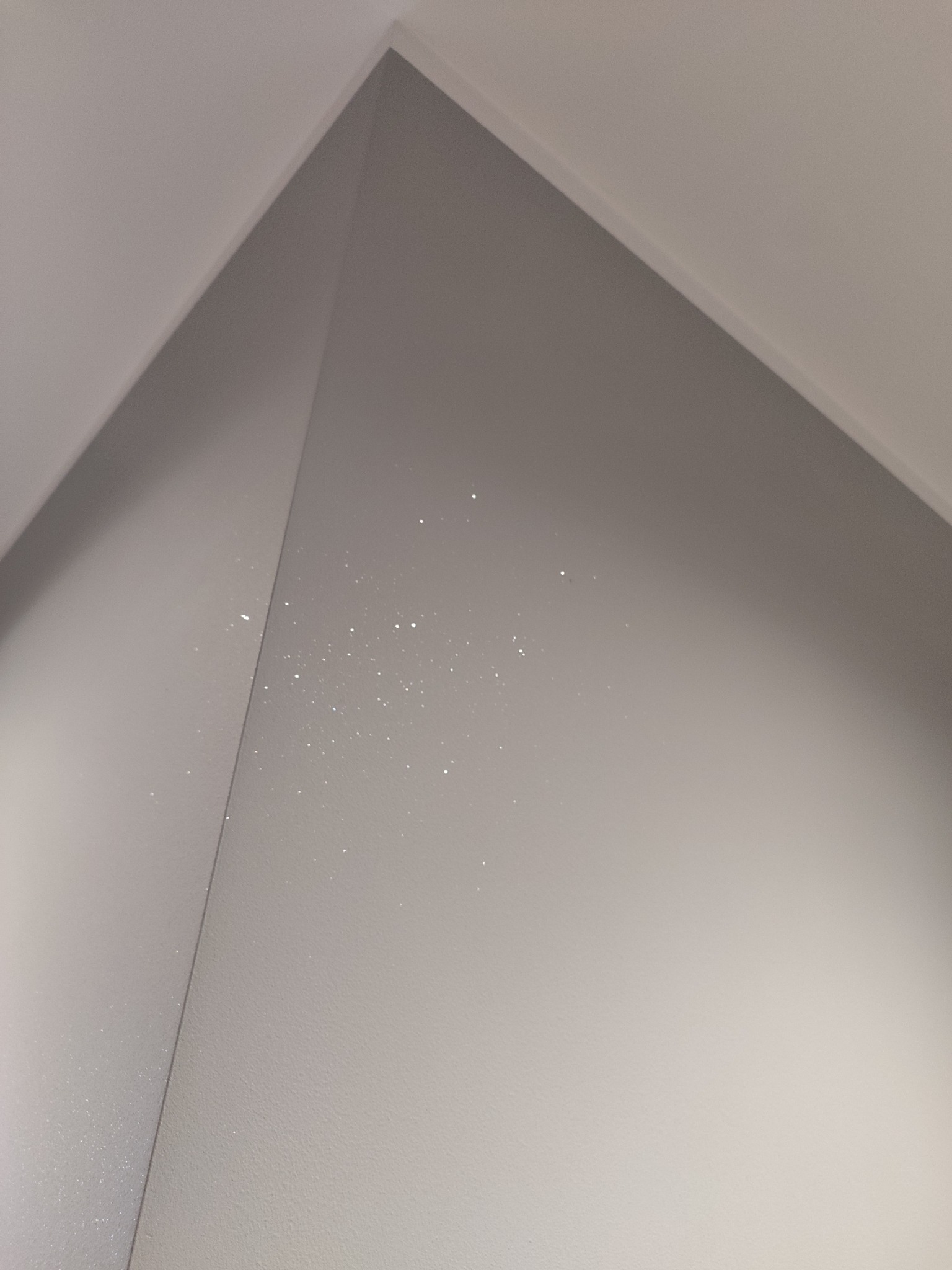 Świeżo pomalowany narożnik ścian w Swarzędzu z widocznymi drobinkami farby, sugerującymi niedawne prace malarskie.