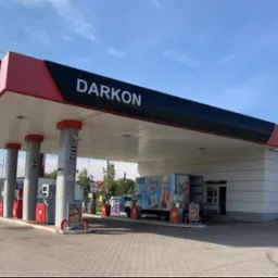 Stacja paliw Darkon w Lubaniu z dystrybutorami, podjazdami i zaparkowanym samochodem dostawczym z reklamą.