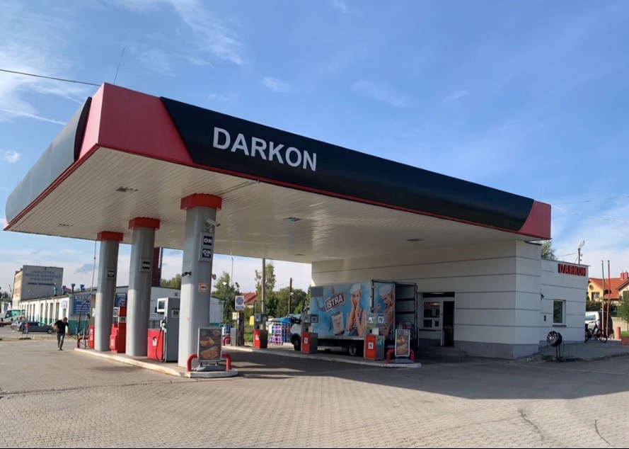 Stacja paliw Darkon w Lubaniu z dystrybutorami, podjazdami i zaparkowanym samochodem dostawczym z reklamą.