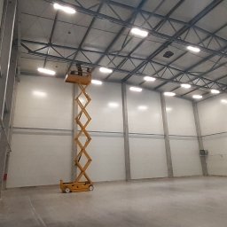 EL- BAR Bartosz Ostrowski - Wysięgnik koszowy wewnątrz hali magazynowej podczas montażu oświetlenia sufitowego LED.